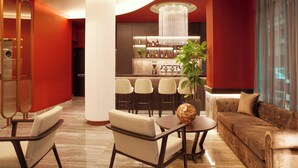 A modern lobby with a bar area, seating arrangements, and a large chandelier. - Zeus Essence Athens Central, Trademark Collection by Wyndham (Athens)