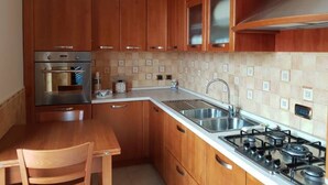A kitchen with wooden cabinets, a stainless steel sink, and a gas stove.