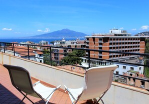 A balcony with two white chairs and a view of a cityscape, including a mountain in the distance. - Sea view, in the center of Sorrento (Sorrento)