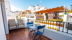 A terrace with a table and chairs, a tiled floor, and a view of neighboring buildings. - Marbella Village  | Studio with Terrace (Marbella)