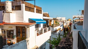 A narrow street with white buildings, a blue awning, and a staircase leading up. - Marbella Village  | Studio with Terrace (Marbella)
