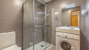 Ein modernes Badezimmer mit einer gläsernen Duschkabine, einer Toilette und einer Waschmaschine.