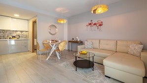 Ein modernes Wohnzimmer mit Sofa, Couchtisch, Essbereich und Küche.