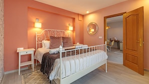 Ein Schlafzimmer mit einem Bett, Nachttischen, einem Spiegel und einer Tür.