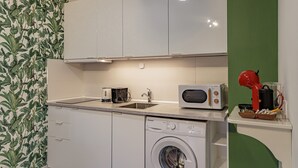 Een kleine keuken met een wasmachine, een magnetron en een spoelbak.