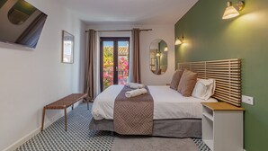 Een slaapkamer met een bed, nachtkastje en uitzicht op een balkon.