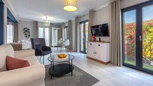 A modern living room with a sofa, coffee table, TV, and dining area. - Casa Ancha 10 | Boho Suite (Marbella)
