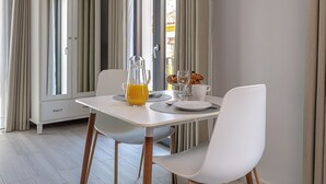 A dining area with a table, chairs, a cabinet, and a window with curtains. - Casa Ancha 10 | Boho Suite (Marbella)