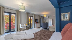 A hotel room with a large bed, a dining area, a kitchenette, and a balcony with a view of flowers. - Casa Ancha 10 | Boho Suite (Marbella)