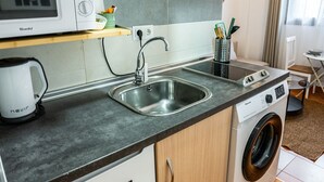 Eine kleine Küche mit Mikrowelle, Spüle und Waschmaschine.