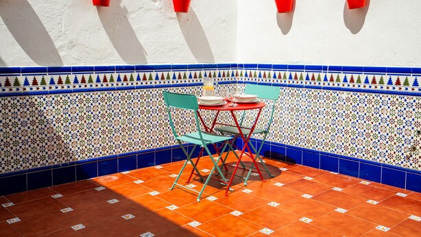 A small patio area with a tiled floor, a folding table, two chairs, and red wall-mounted planters. - Bermeja Village  | Apartment with patio (Marbella)