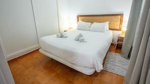 A hotel room with a large bed, a wooden headboard, and a nightstand with a lamp. - Bermeja Village  | Apartment with patio (Marbella)