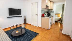 A compact hotel room with a TV, a small kitchen area, a washing machine, and a bed. - Bermeja Village  | Apartment with patio (Marbella)