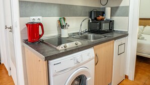 A compact kitchen with a washing machine, a coffee maker, and a microwave. - Bermeja Village  | Apartment with patio (Marbella)