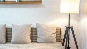 A neatly arranged bedroom with a bed, bedside table, lamp, and shelves with books. - Bermeja Village  | Apartment with patio (Marbella)