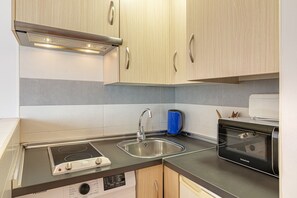 Una cocina compacta equipada con microondas integrado, tostadora y lavavajillas.