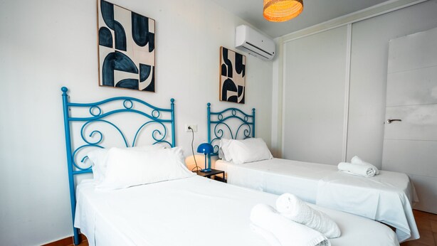 A hotel room with two beds, white bedding, and blue metal headboards.