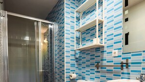 A bathroom with a glass-enclosed shower, a toilet, and a sink. - Escuela Village | Budget Quadruple Apartment (Marbella)