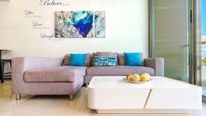 Una sala de estar moderna con un sofá seccional gris, cojines color turquesa y una mesa de centro blanca con objetos decorativos.
