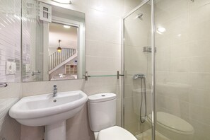 A bathroom with a white sink, toilet, and glass-enclosed shower.