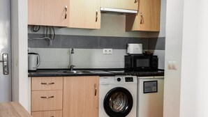 Una cocina compacta con armarios de madera, lavadora y microondas.