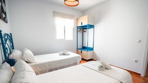 Un dormitorio con dos camas, un armario y una ventana.