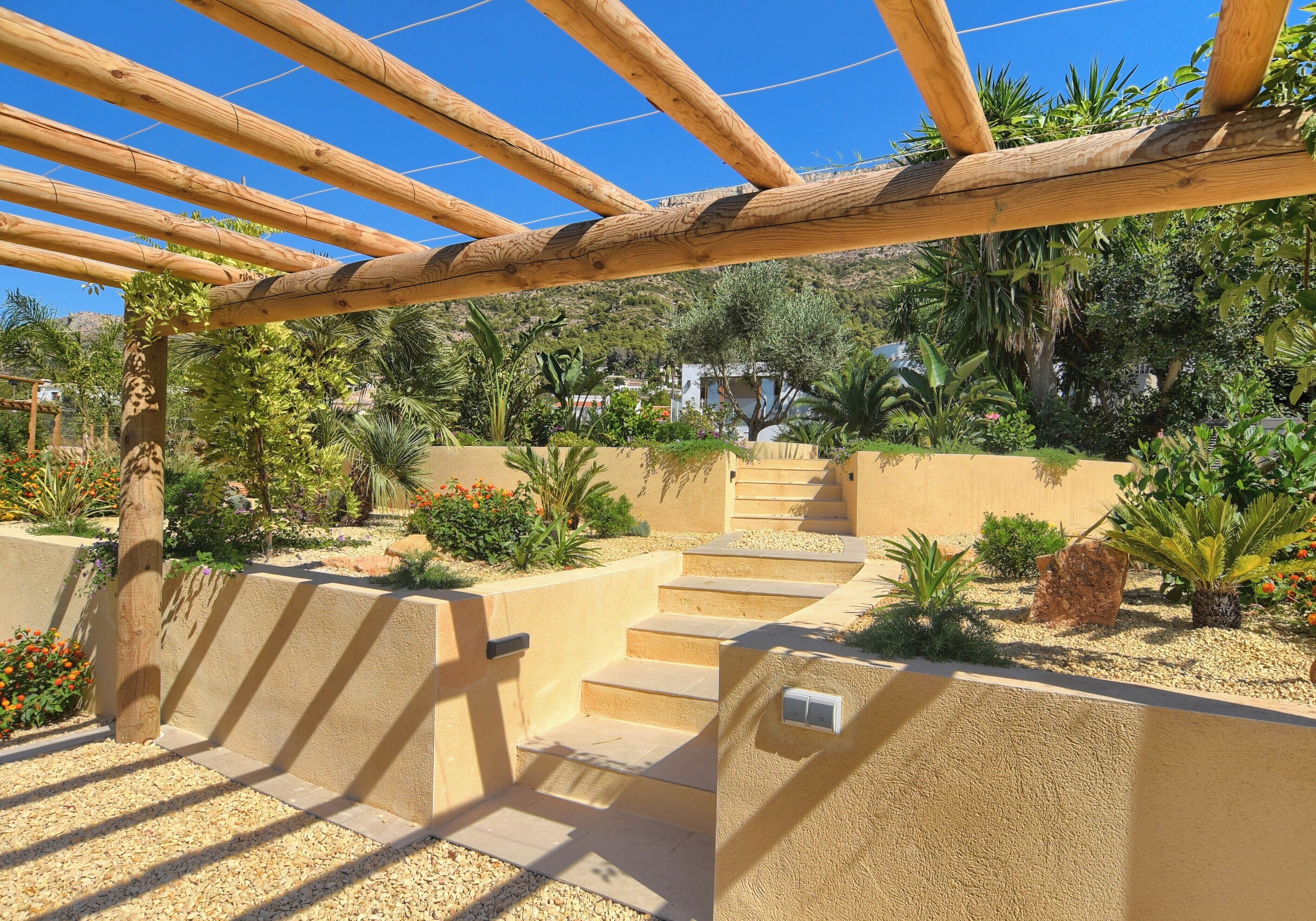 A wooden pergola structure with steps leading to a garden area.
