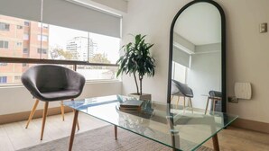 Ett modernt rum med ett glasbord, en stol, en krukväxt och en stor spegel.