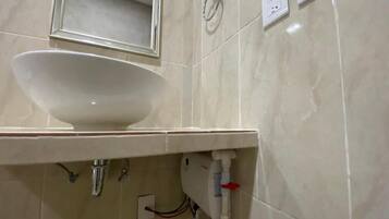 Un baño con lavamanos blanco, espejo y perchero.