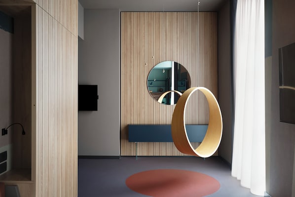 A modern room with a wooden panel wall, a round mirror, a blue bench, and a red circular rug. - 21 House of Stories Navigli (Milan)