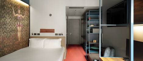 Quarto de hotel com cama, escrivaninha, televisão e guarda-roupa.