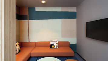 Una sala de estar moderna con un sofá seccional, una mesa redonda de centro y un televisor de pantalla plana montado en la pared.