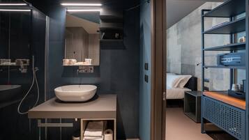 Un bagno moderno con un lavandino bianco ampio, uno specchio e uno scaffale con articoli da toilette.