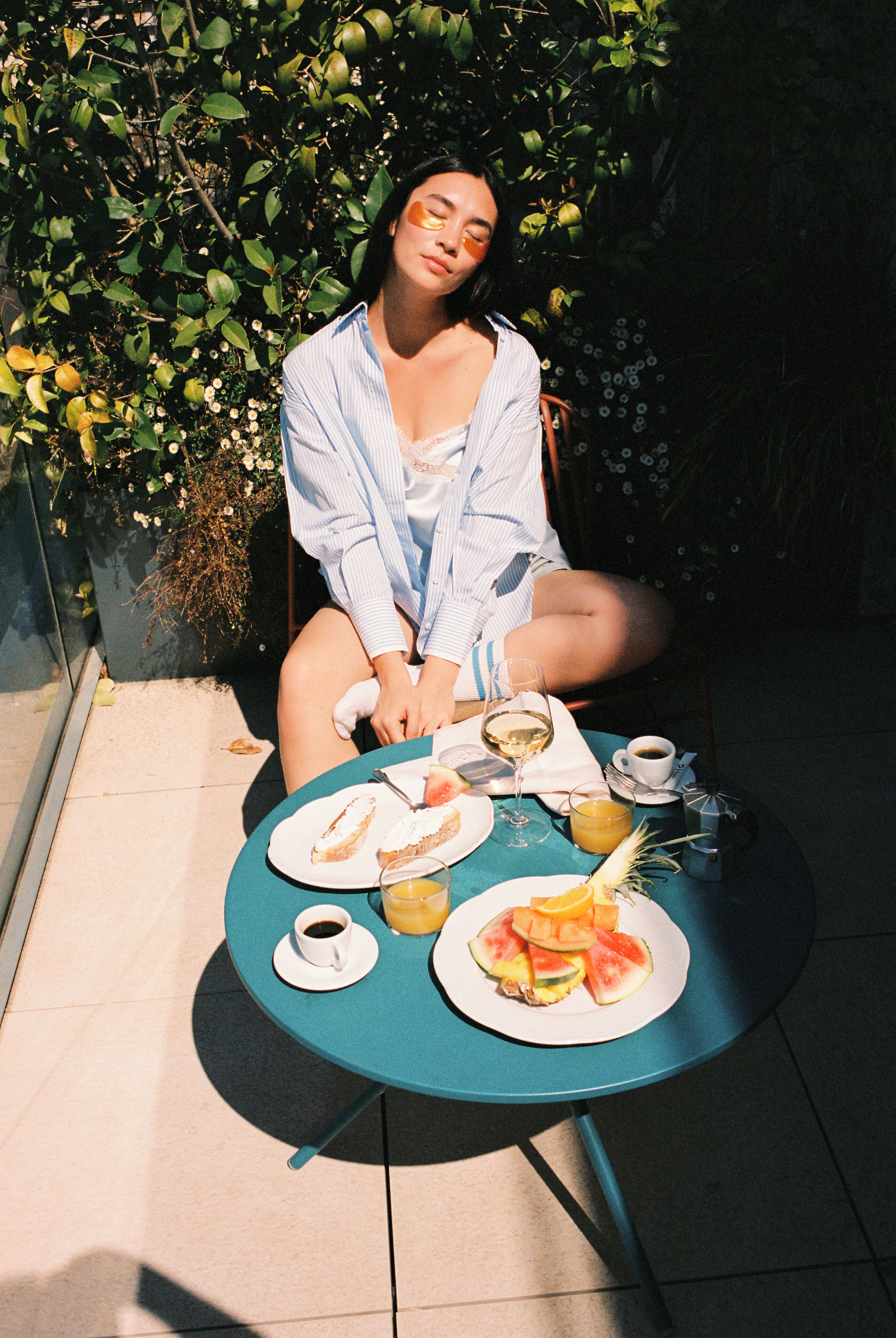 A person seated at a round table with a plate of food, a glass of wine, and a cup of coffee.