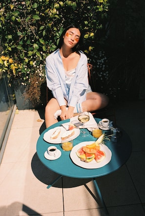 A person seated at a round table with a plate of food, a glass of wine, and a cup of coffee. - 21 House of Stories Navigli (Milan)