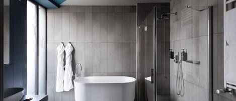 Un baño moderno con una bañera independiente, ducha con mampara de vidrio y un amplio ventanal que proporciona luz natural.