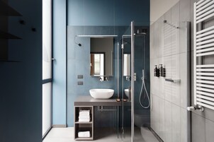 Een moderne badkamer met een douchecabine van glas, een groot wit wastafelmeubel en een handdoekrek.