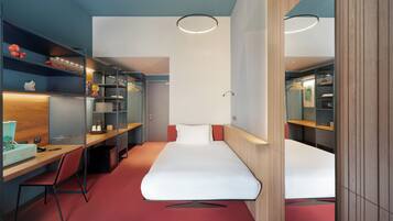 Une chambre d’hôtel moderne équipée d’un lit, d’un bureau et d’une armoire.
