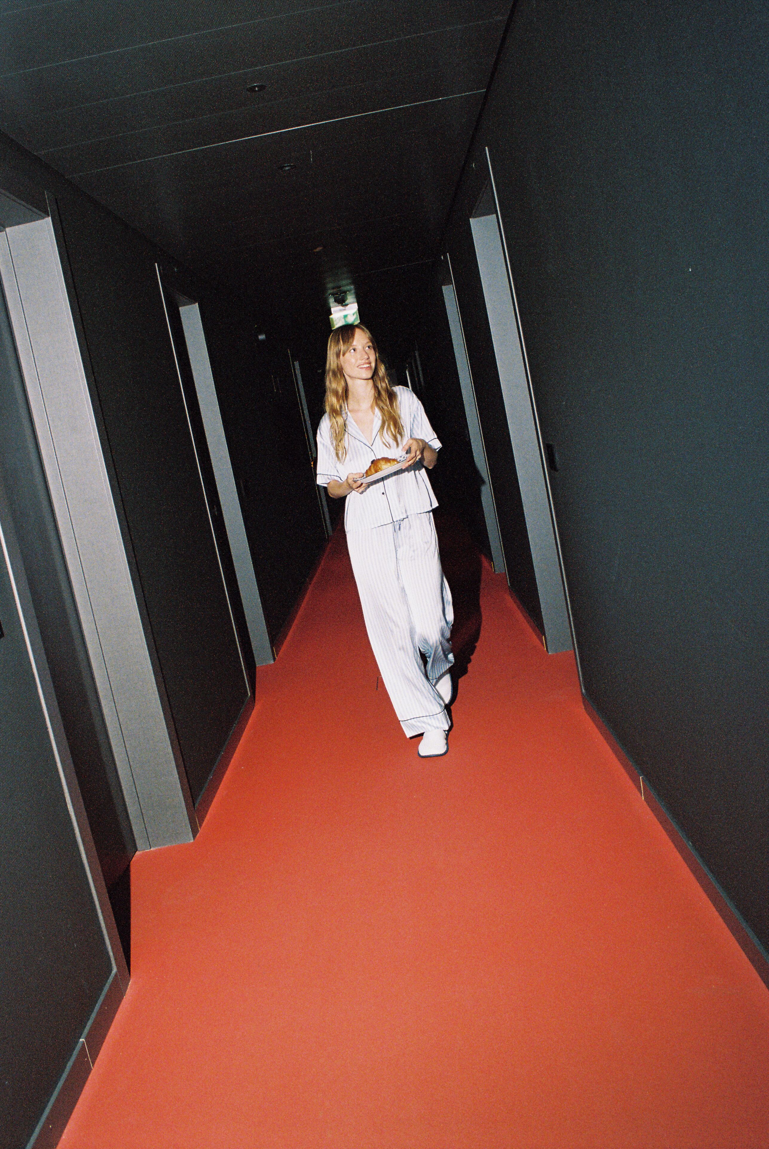 A person walking down a corridor with a red carpet.