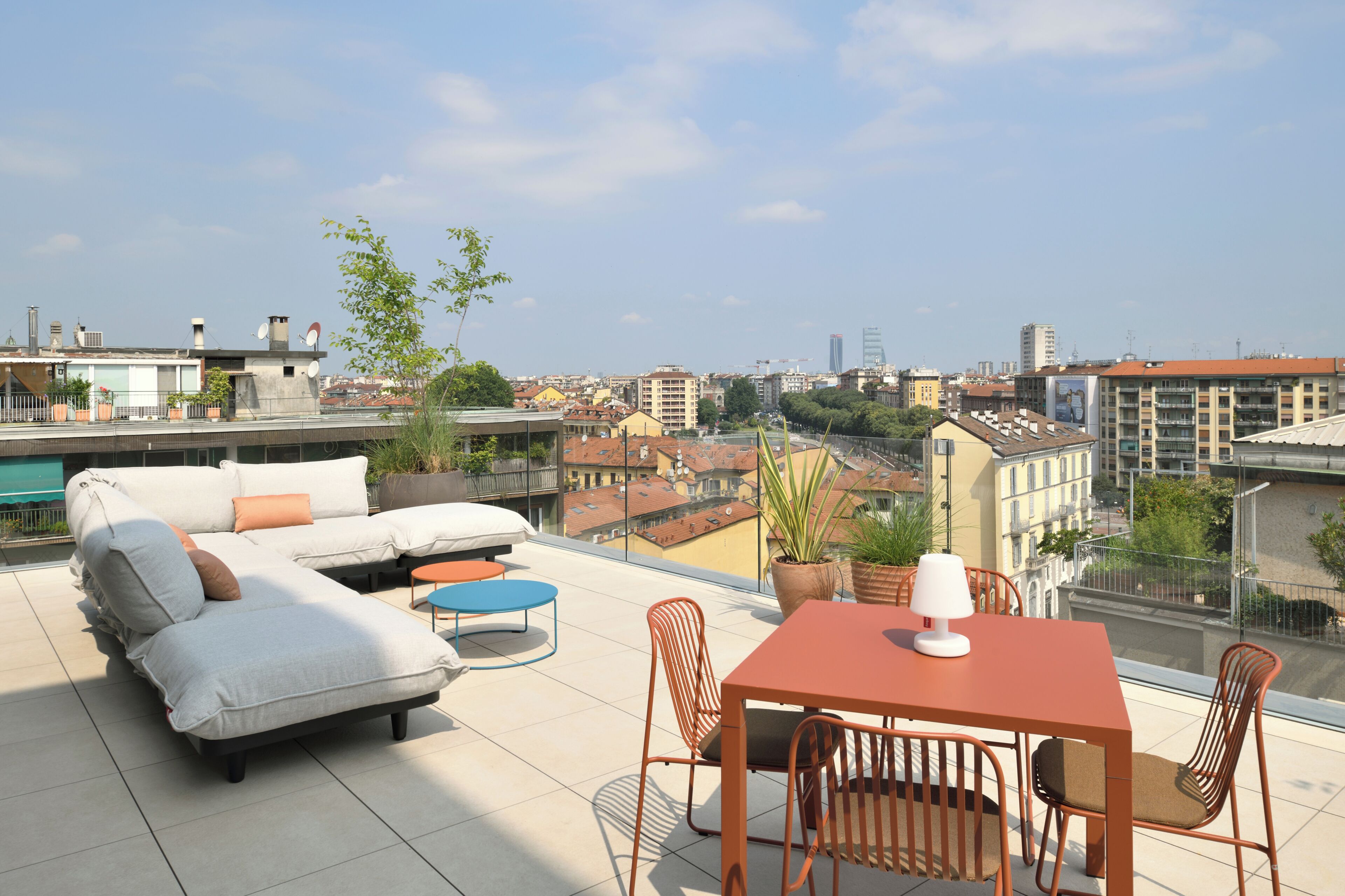 Una terrazza sul tetto con divani, un tavolo e sedie, e piante in vaso.