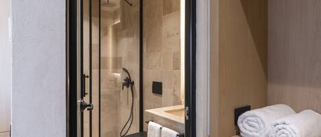 Une salle de bain moderne dotée d’une douche à parois de verre, de toilettes et d’un lavabo avec un porte-serviettes.