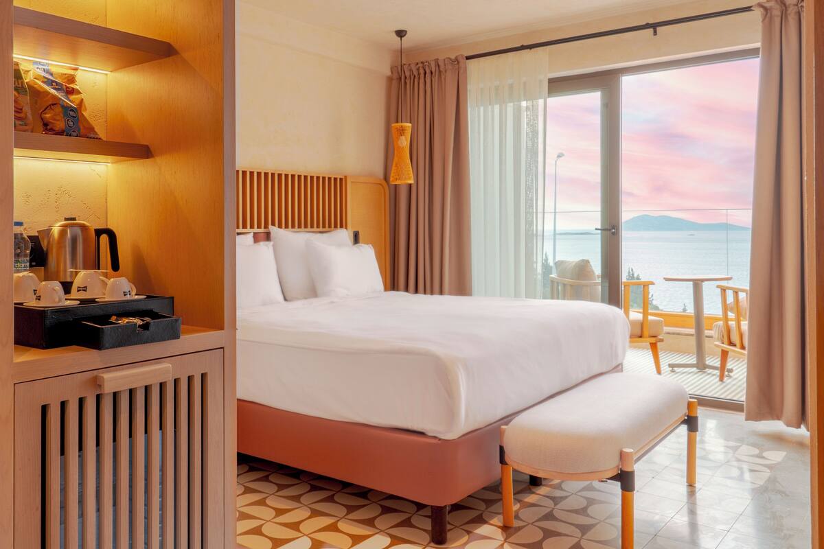 Una habitación de hotel con cama, mesita de noche y vistas al mar.