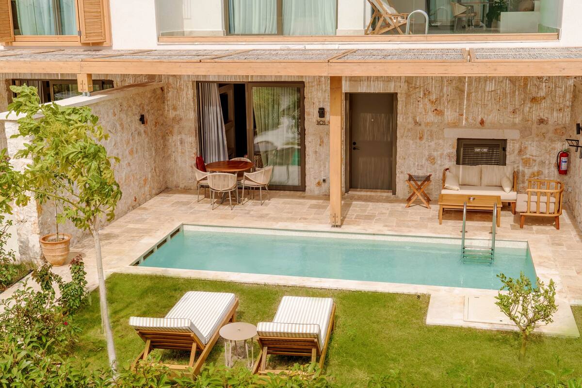 Zona de piscina con sillones de descanso, una mesa y un extintor.