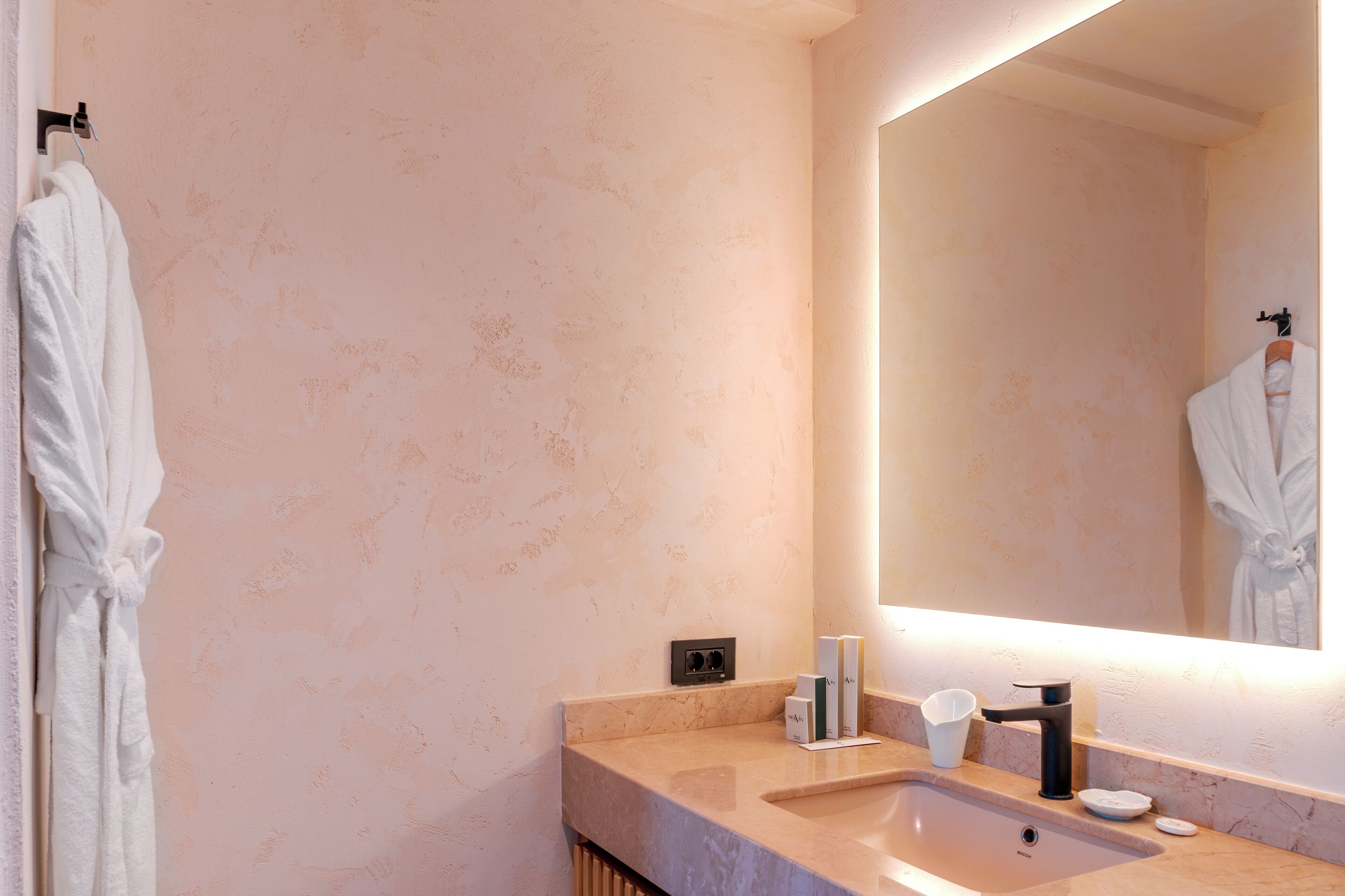 Un baño con un lavabo de mármol, un espejo y un perchero para toallas.