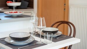 Ruokapöytä on katettu lautasilla, kulhoilla, laseilla ja aterimilla.
