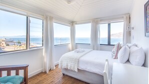 Ein Schlafzimmer mit einem großen Bett, Meerblick und Holzboden.