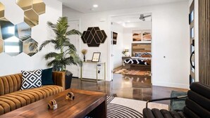 A modern living room with a wooden coffee table, a leather sofa, and a large potted plant. - The Compass Rose: Luxury home, Hot Tub, Pickleball (Hurricane)