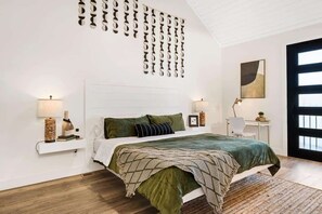 A modern bedroom with a large bed, a wall-mounted light fixture, and a large window.