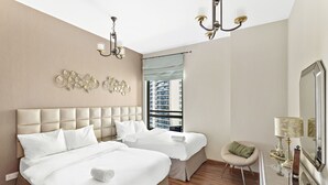 A hotel room with two beds, a sitting area, a large mirror, and a view of the city. - WelHome - Waterfront Family-Size Apt With JBR Beach Access (Dubai)