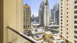A high-rise building with a unique architectural design, a marina in the background, and a clear sky. - WelHome - Waterfront Family-Size Apt With JBR Beach Access (Dubai)